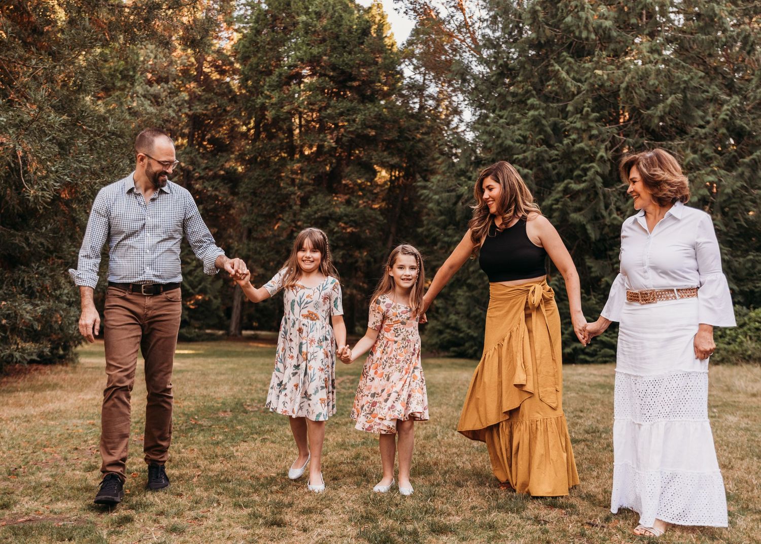 Family walking together through a sunlit forest clearing in coordinated outfits.