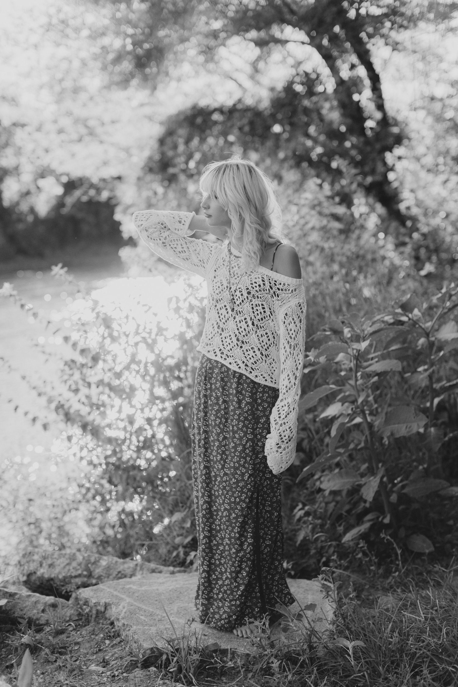 Dreamy black and white image of person in lace top and flowing skirt against misty nature backdrop.