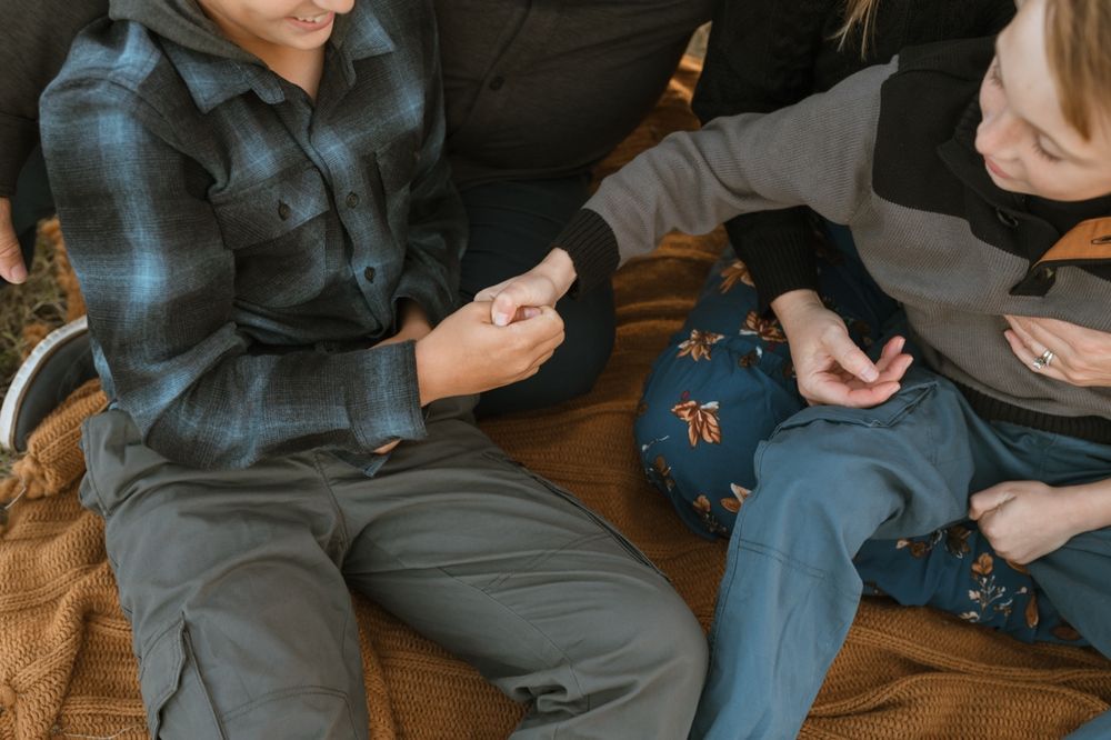 People sitting on wooden floor with a brown dog resting beside them.