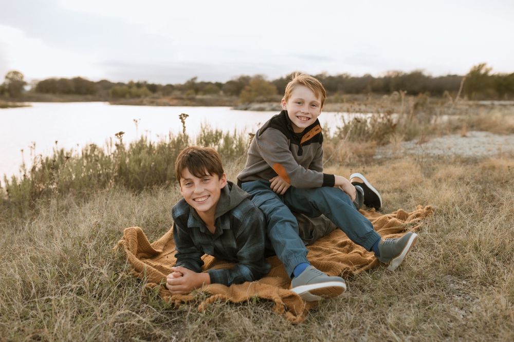 A family and their dog share a joyful moment together on a grassy hill during golden hour.