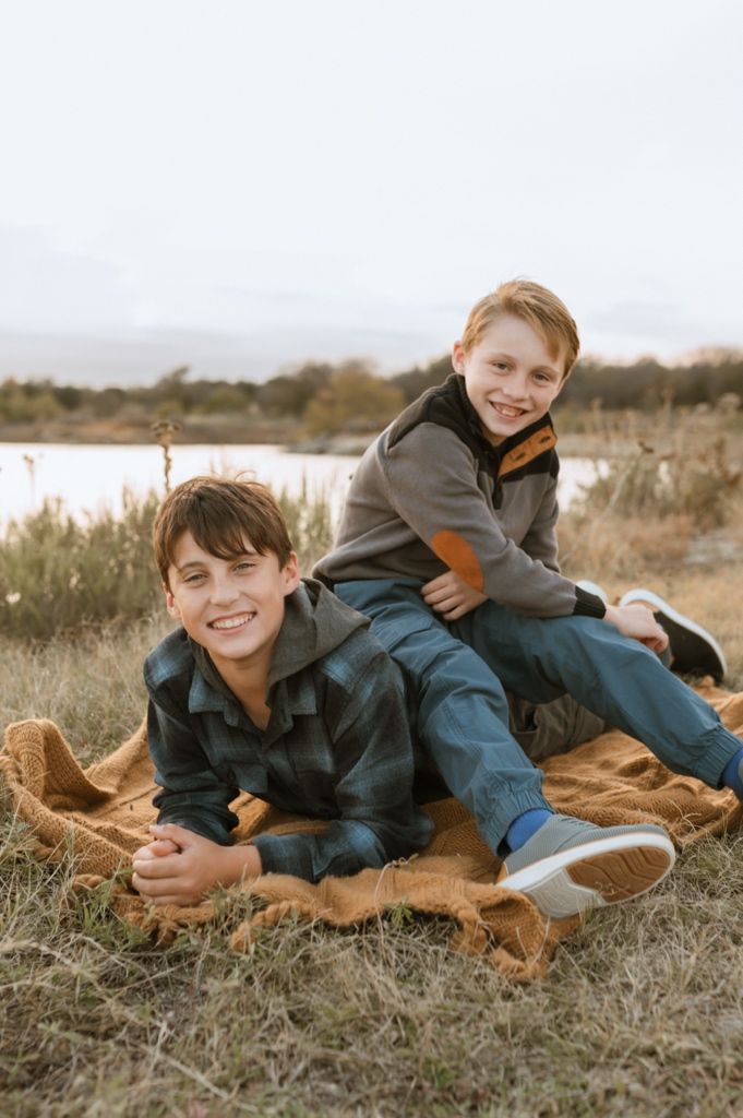 Children and dog lying in brown grass during casual outdoor photography session.