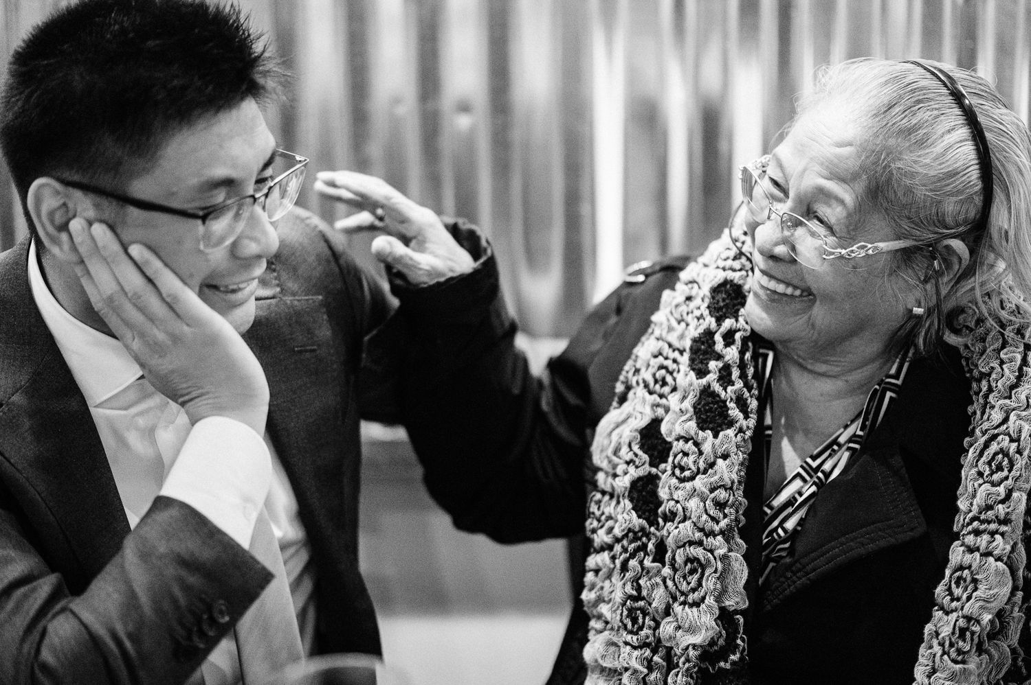 A candid black and white photo showing a heartwarming moment of laughter between a groom and family member