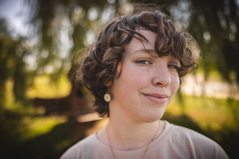 A series of seven outdoor portrait photos showing someone with curly hair at sunset with trees in the background.