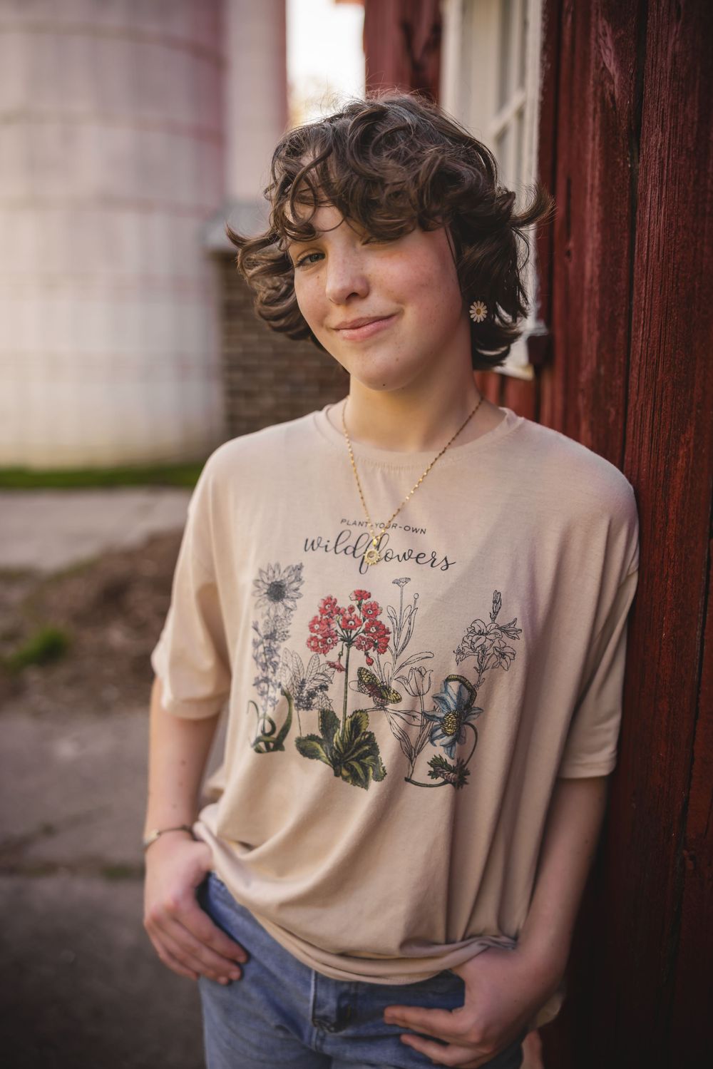 Person wearing a beige t-shirt with wildflower and butterfly design against a blurred background.