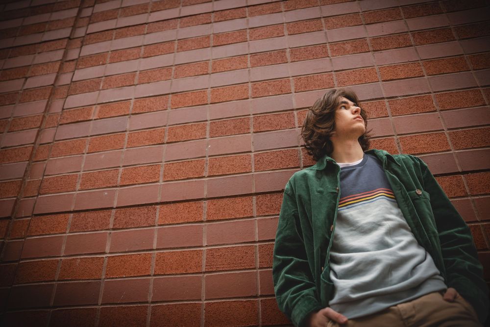 Artistic series of poses against rustic brick wall in casual urban fashion.