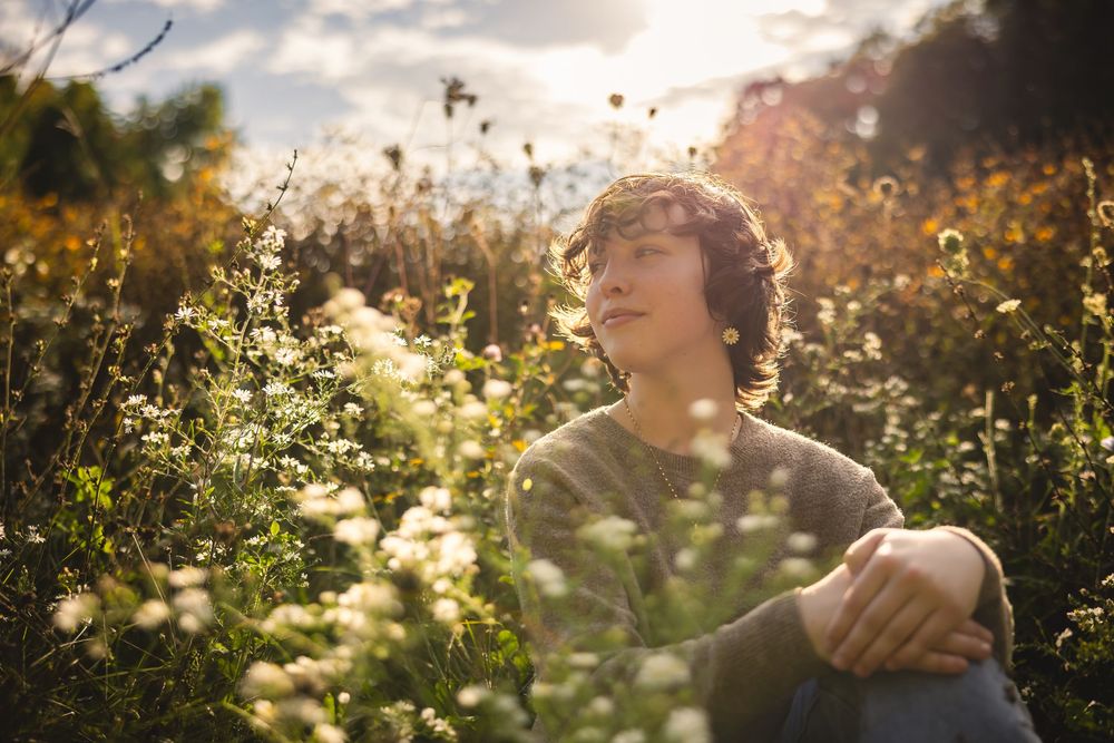 Dreamy outdoor portrait with sunlit wildflowers and golden hour lighting.