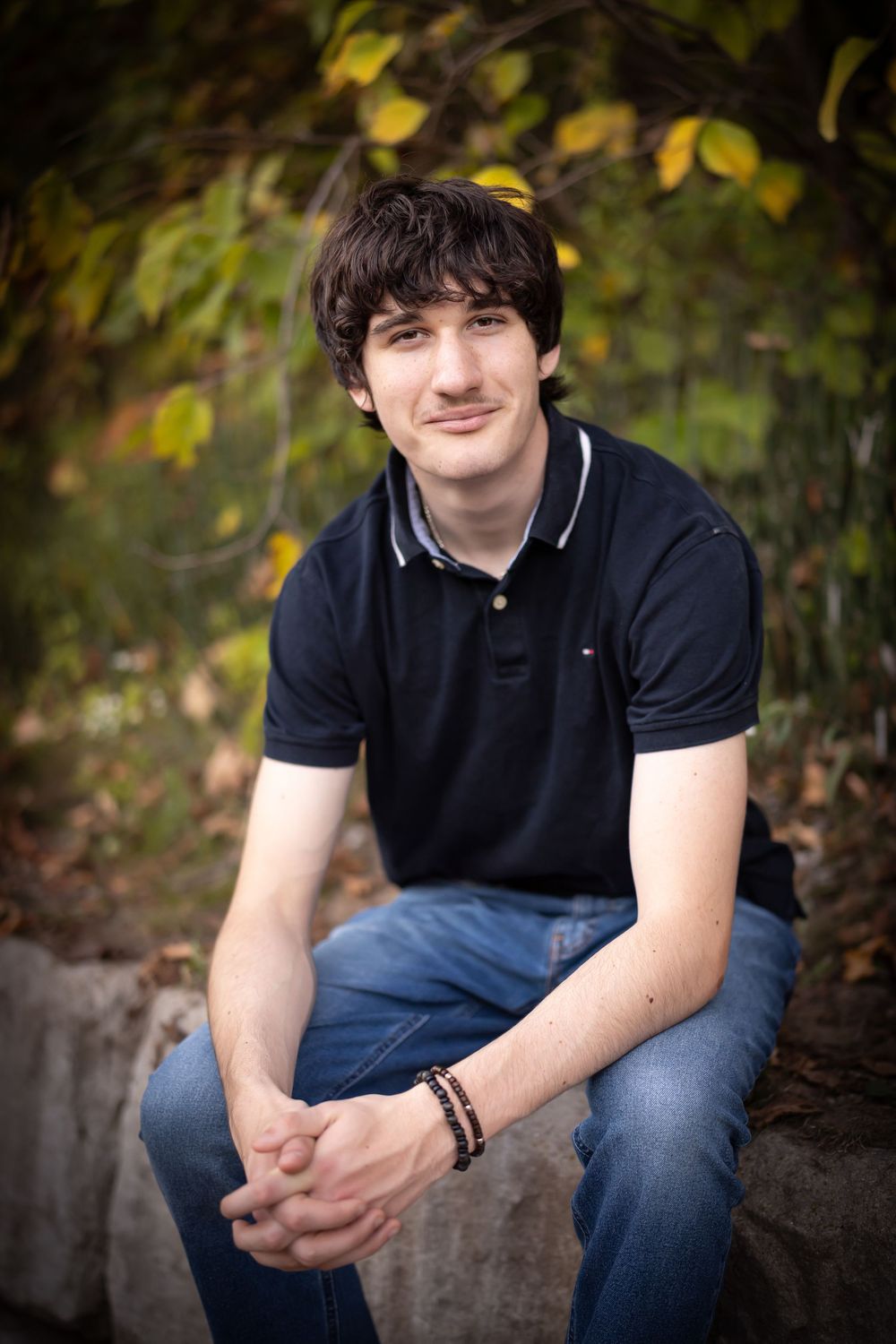 A casual portrait series in a natural outdoor setting with autumn foliage in the background.