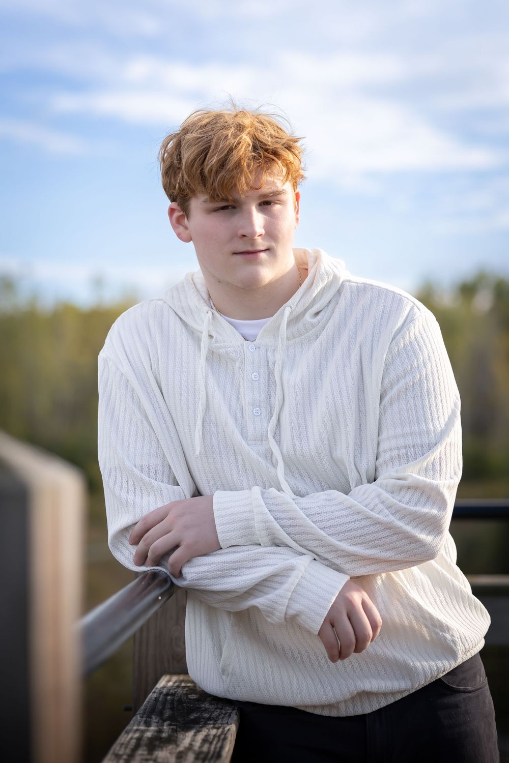 Portrait against natural background wearing white ribbed sweater.