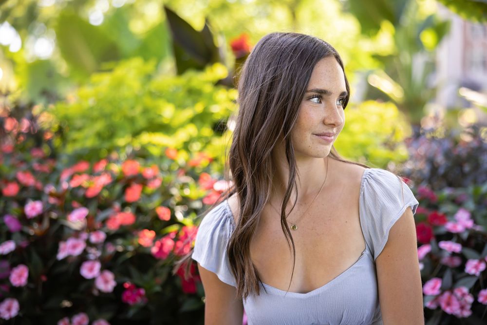 Summer portrait session with pink flowers and natural sunlight filtering through trees.