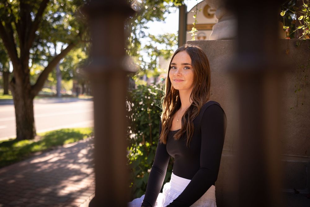 Artistic portrait through architectural columns with natural backlighting.