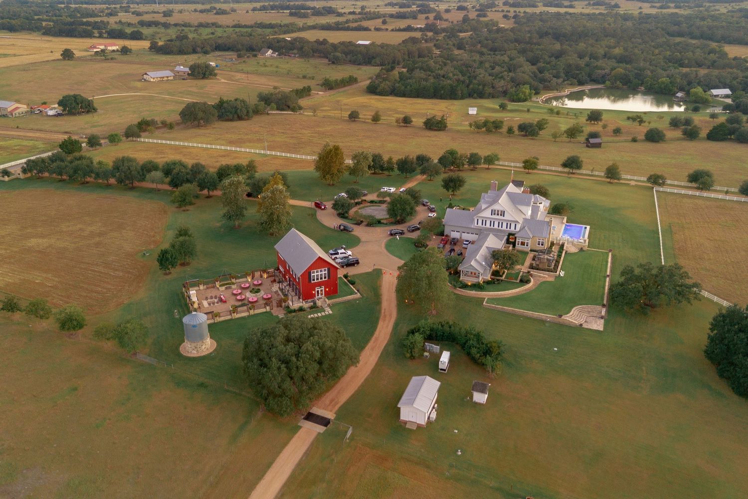 Aerial view of a rural landscape with scattered farmhouses, barns, and agricultural fields stretching across rolling terrain.