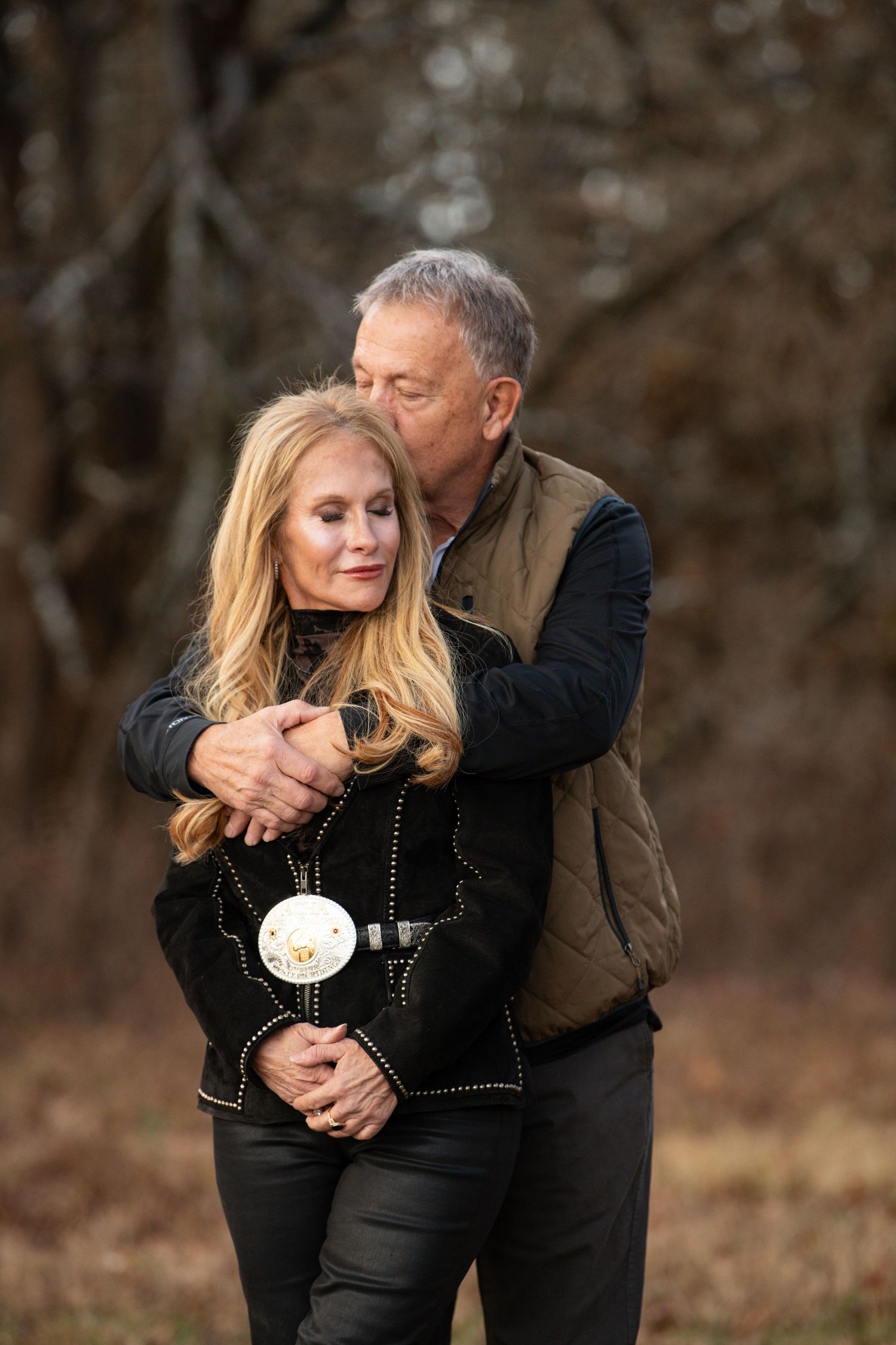 Romantic couple portrait session among bare trees in autumn setting.