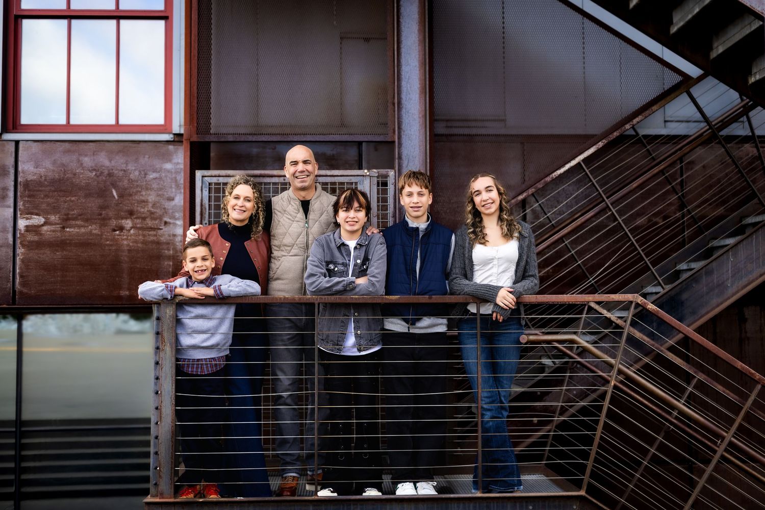 A group of people stand together on a staircase in an industrial or office building setting.