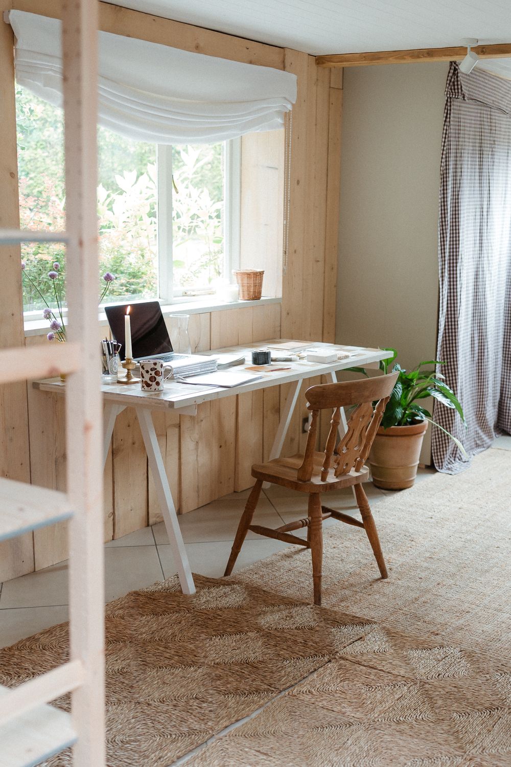 Modern minimalist home office space with wooden walls, white desks, and natural light streaming through windows.