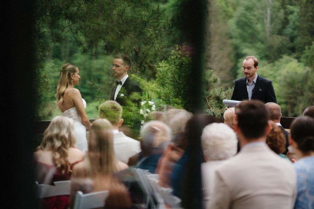 Blurred wedding ceremony scene in a green outdoor forest setting.