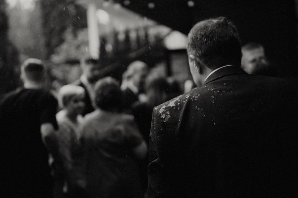 Black and white candid shot of wedding guests mingling at an evening reception.