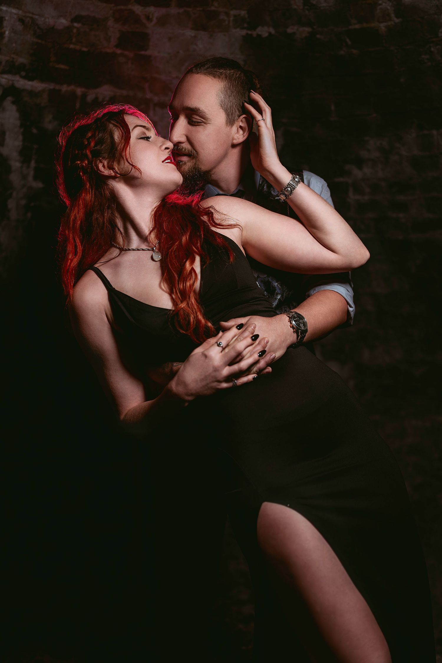 Intimate couple embracing in dramatic low-key lighting against dark background creating romantic silhouettes.