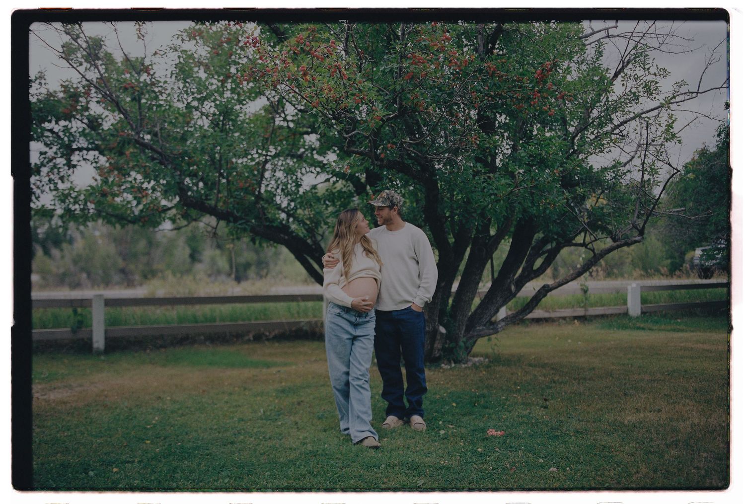 A couple walks through a vibrant field of yellow wildflowers with mountains in the background.