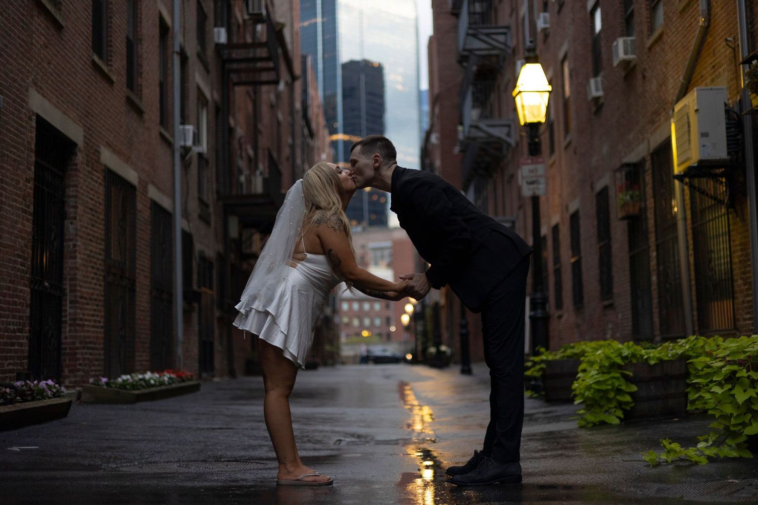 A romantic couple dances together on a cobblestone street in Boston's historic Acorn Street at dusk.