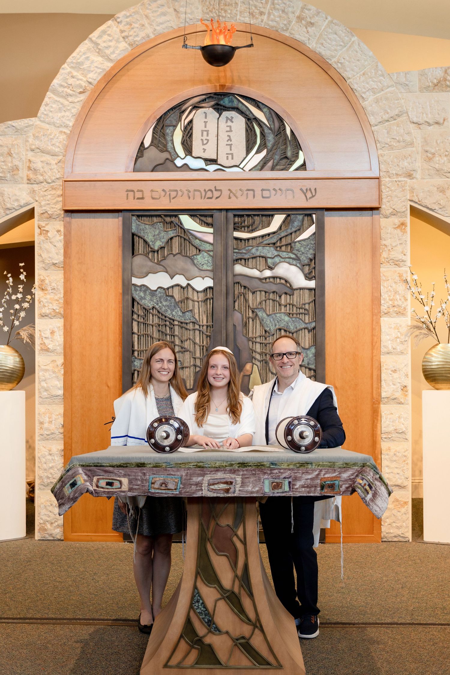 A family portrait series taken at a synagogue entrance with stone archways and decorative Hebrew text above.