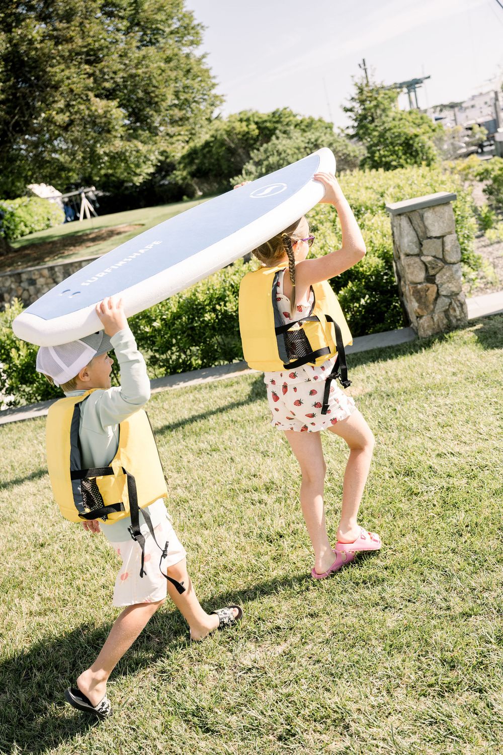 Two cosplayers playfully pose with a long white fabric prop in a sunny grassy outdoor setting.