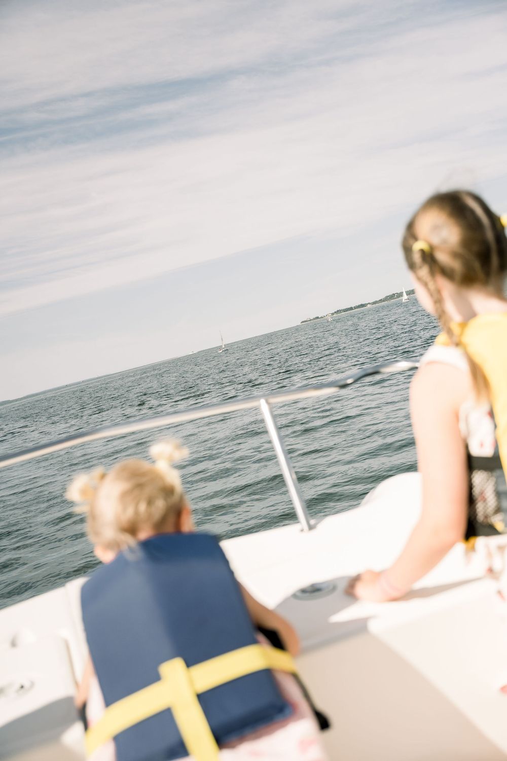 People relaxing on the deck of a boat while cruising across calm ocean waters on a sunny day.