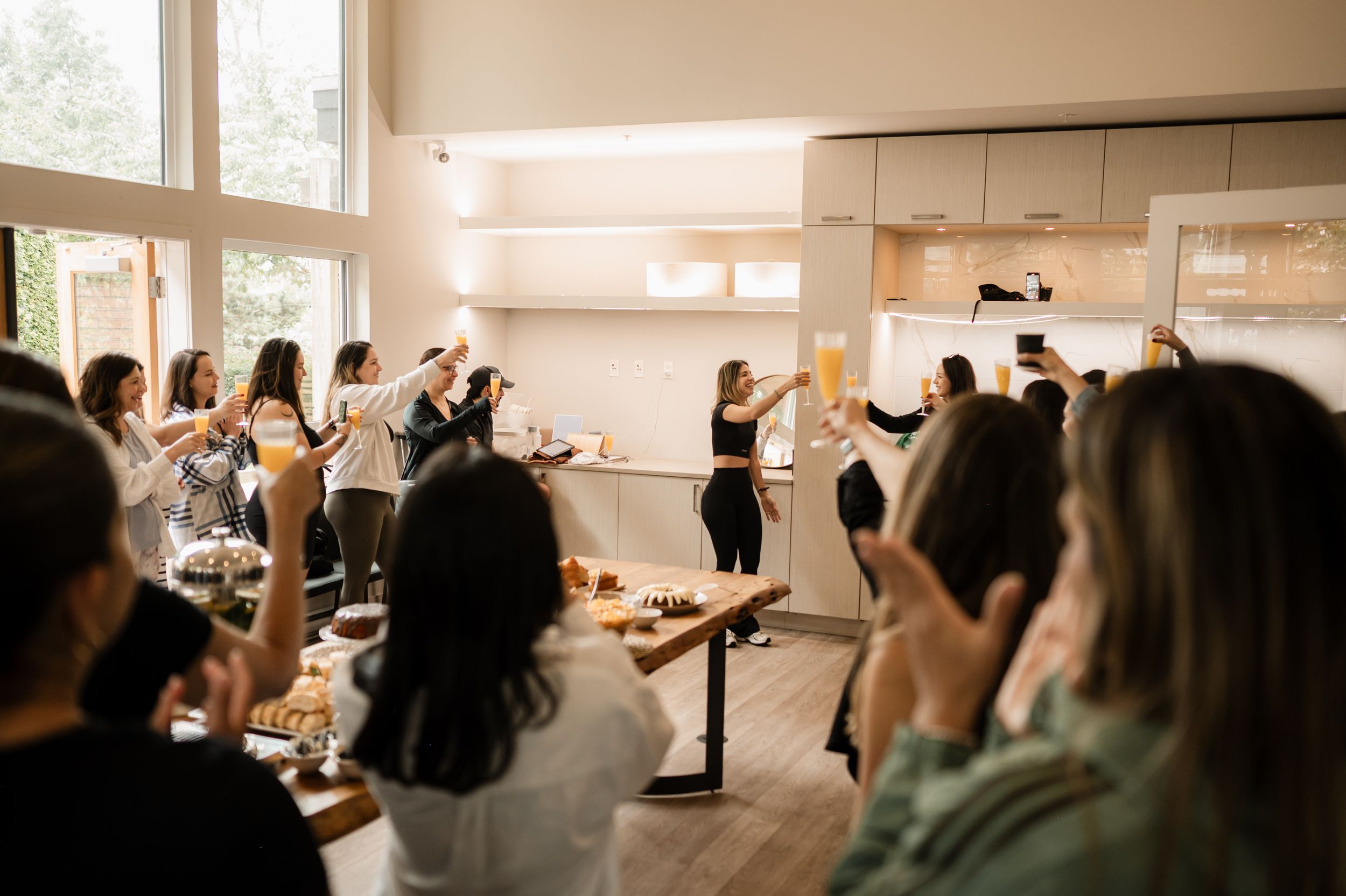A group of people raising their hands in a bright indoor space during a celebratory event.
