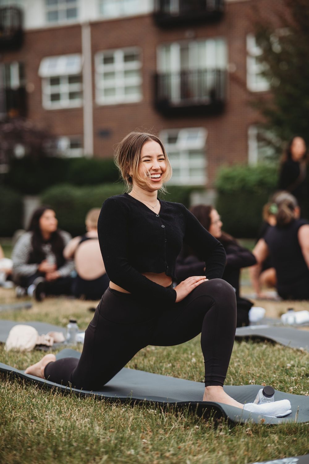 Group fitness class participants stretching on yoga mats outdoors.