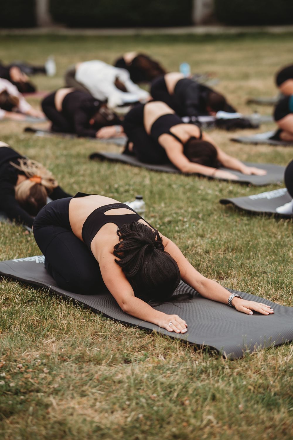 People practicing child's pose during outdoor yoga session on mats.