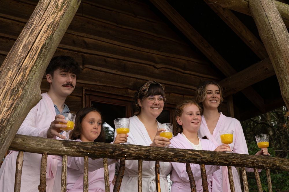 People in traditional German dress sit at a wooden table with beer glasses during what appears to be Oktoberfest.