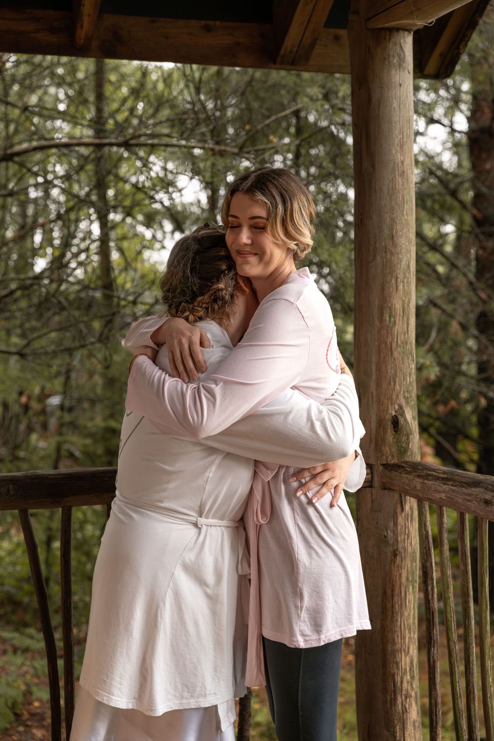 A sequence of photos showing two people in light colored clothing sharing warm embraces in a wooded outdoor setting.