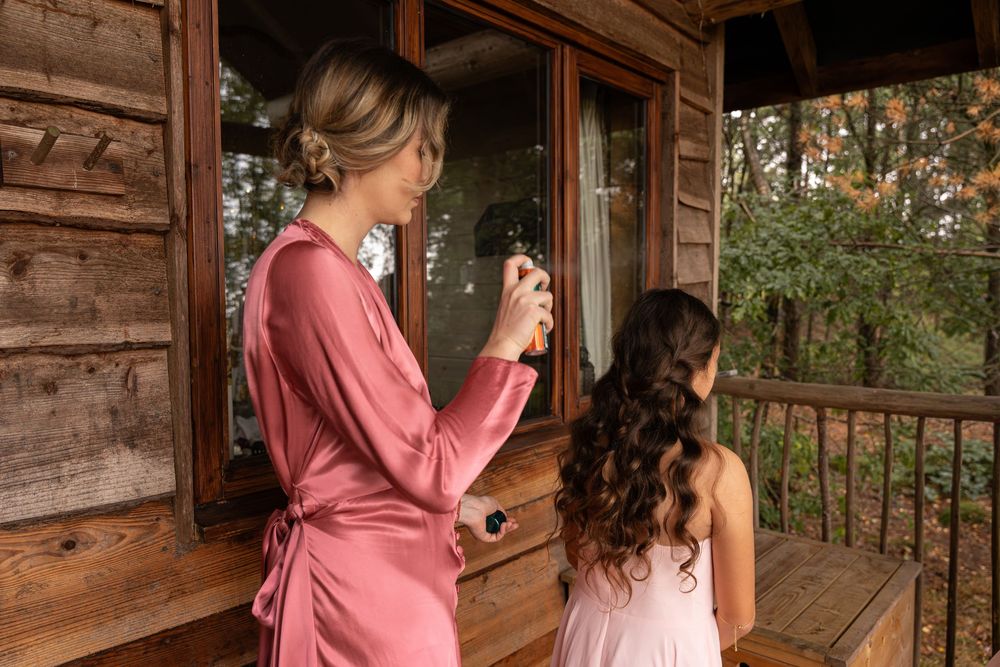 Two people in pink and burgundy clothing sit on a wooden porch overlooking nature.