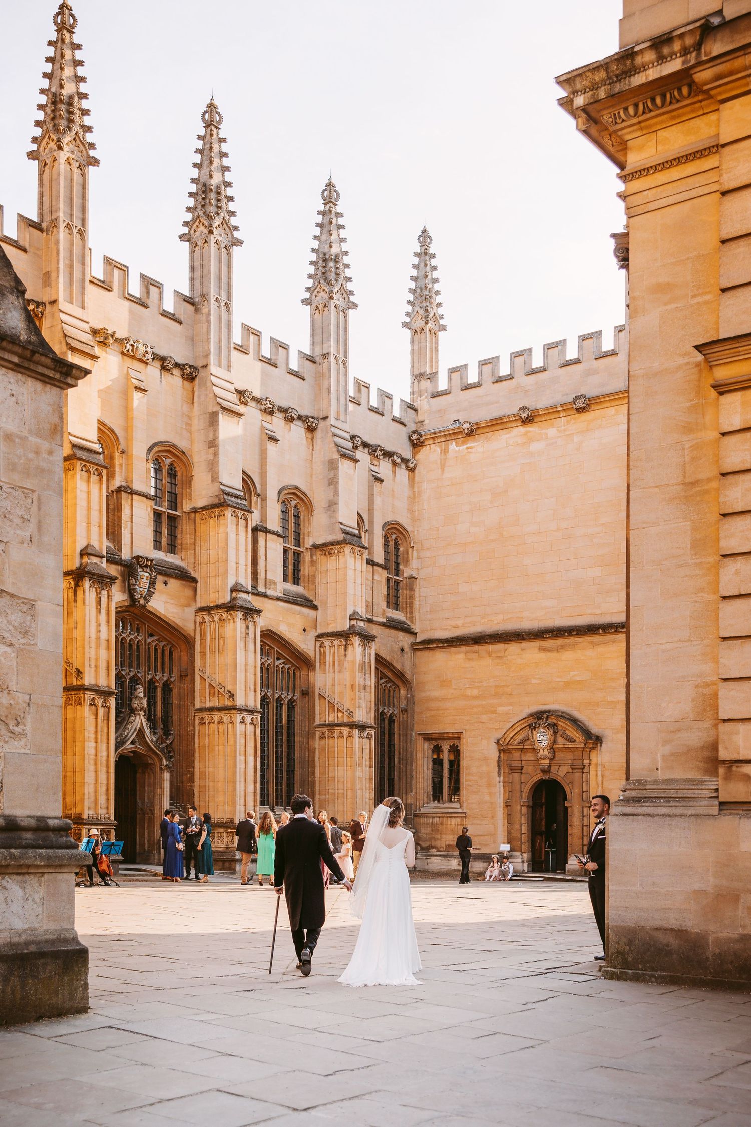 Gothic stone architecture and spires of Oxford University's courtyard captured in warm golden light at sunset.