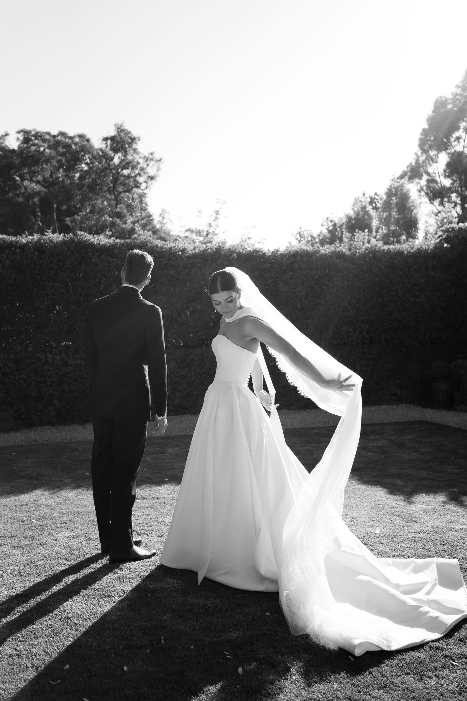 A series of romantic black and white wedding photos showing a couple's silhouettes against sunlit grass.