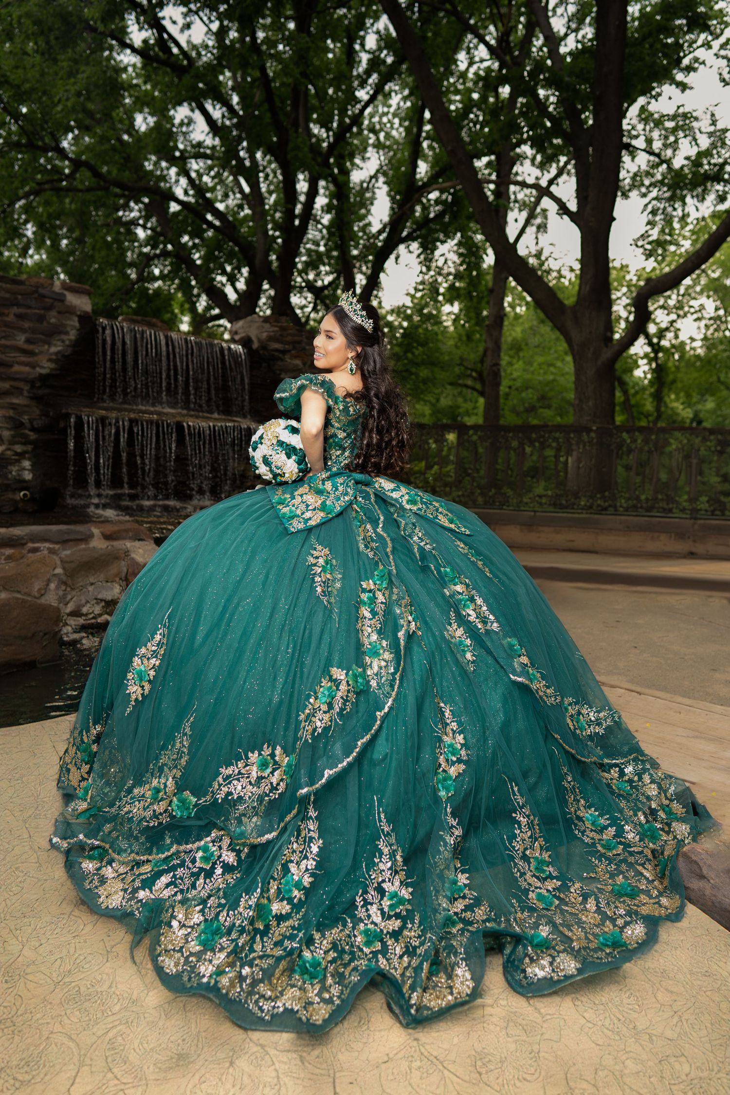 Stunning teal quinceanera dress with silver embroidery photographed by waterfall.
