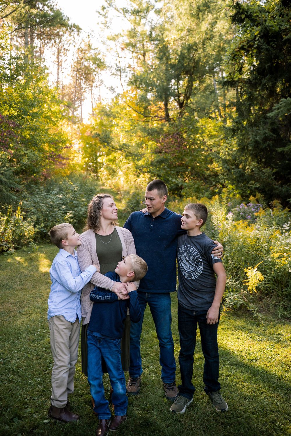 A group stands together on a nature trail during golden hour with sunlight filtering through the trees.