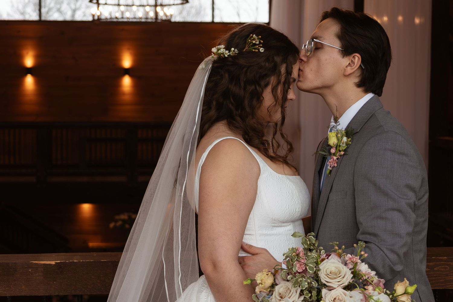 Intimate wedding portrait in rustic venue with warm lighting and wooden details.