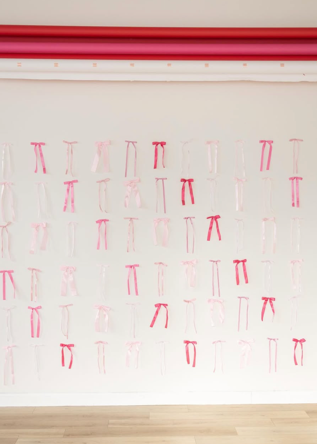 Pink and white paper lanterns hang from a ceiling in a decorative pattern against a white background.