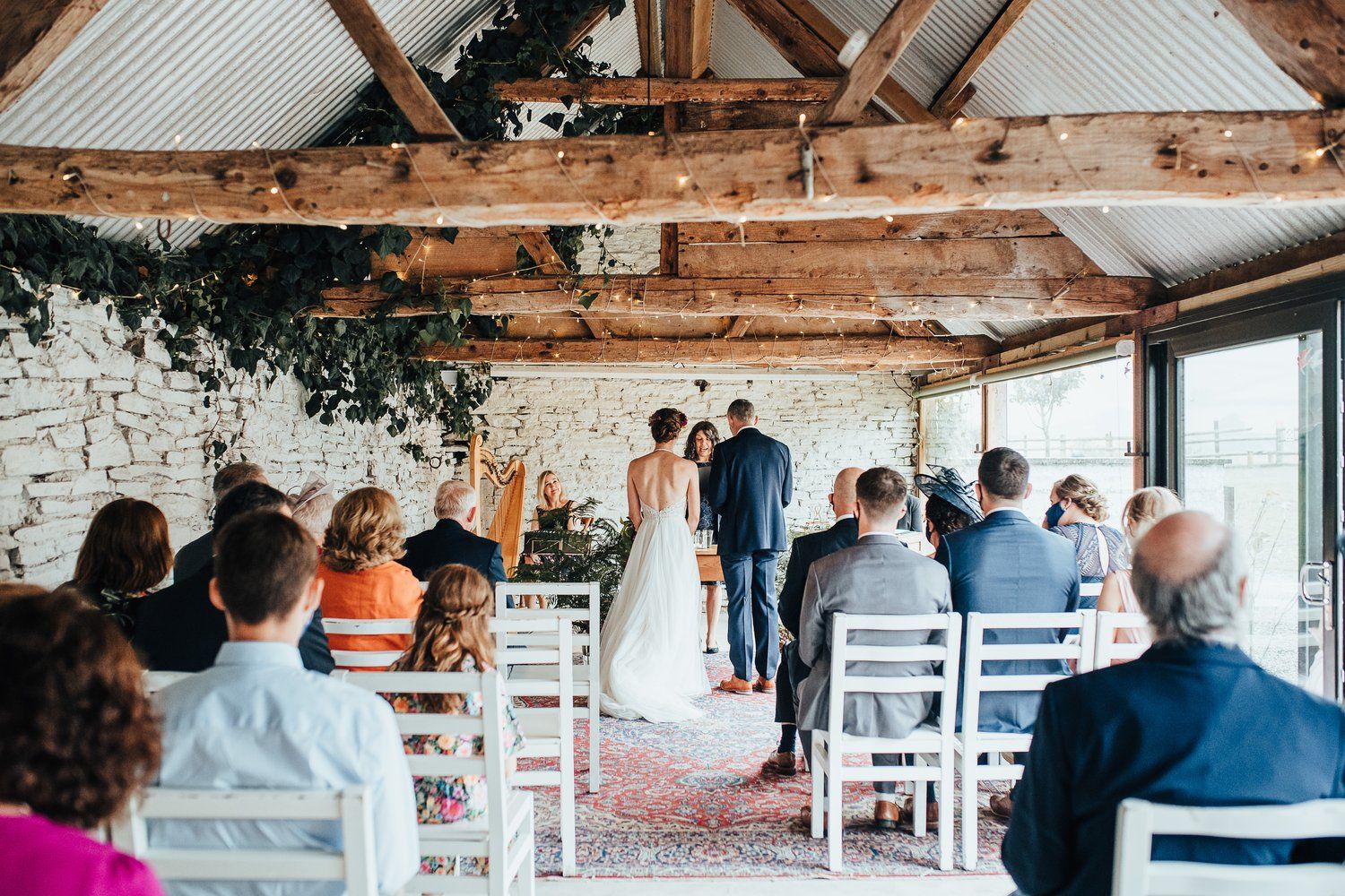 Wedding ceremony setup in a rustic barn venue with exposed beams and brick walls.