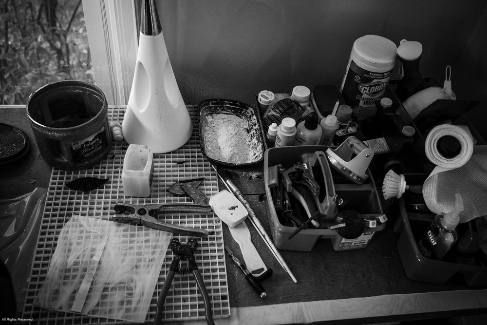 Black and white photo sequence showing hands preparing coffee using a pour-over setup on a counter.