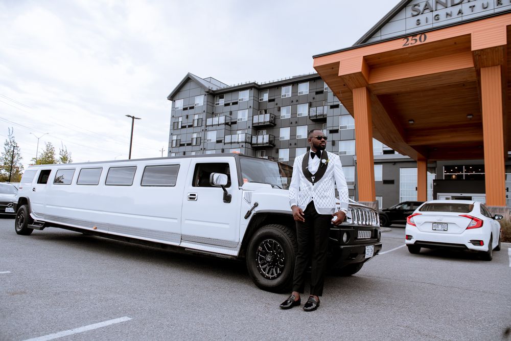 A white stretch Hummer limousine parked outside a hotel entrance with figure standing next to it.