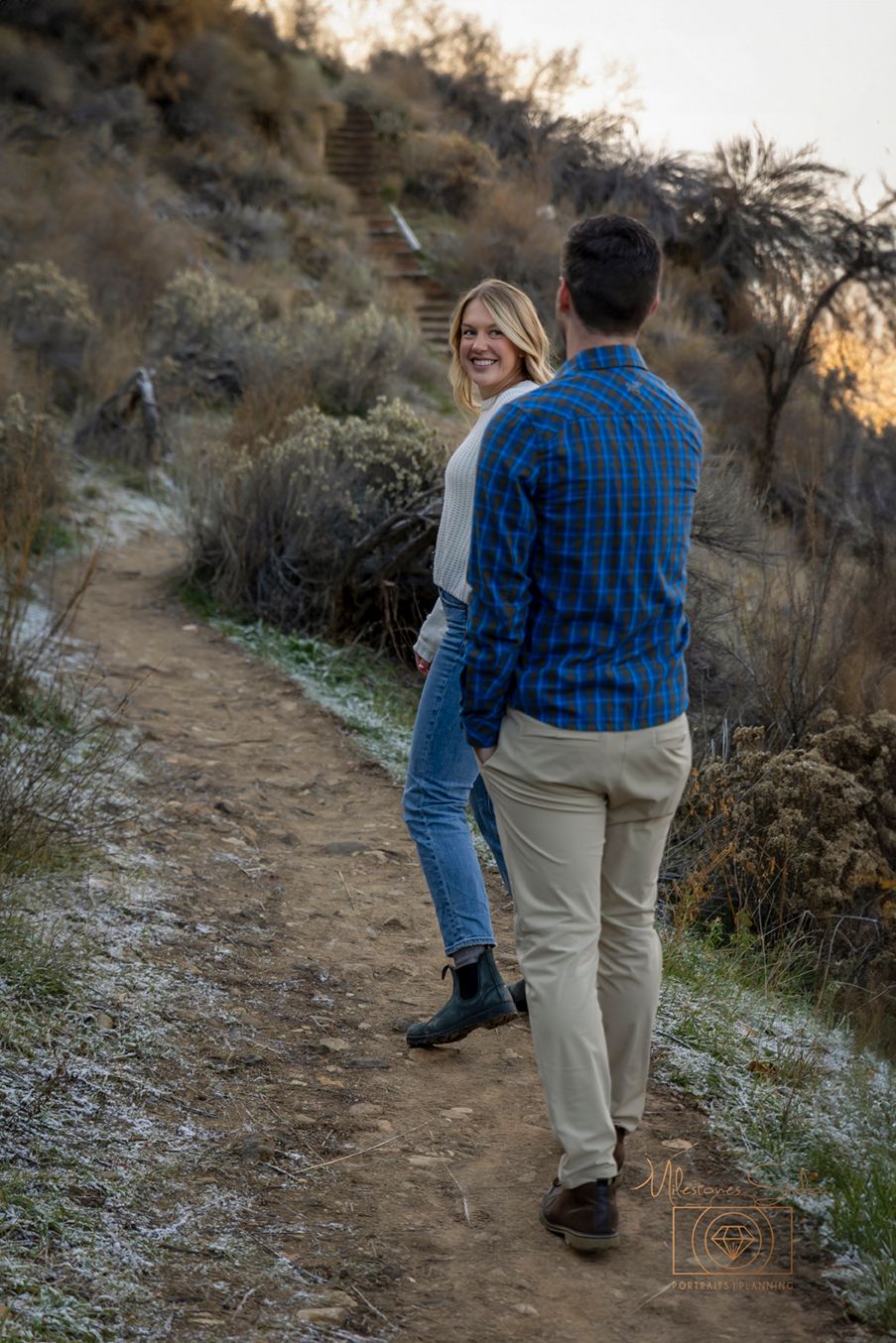 Woman leading man and looking back at him for engagement photos in Boise foothills