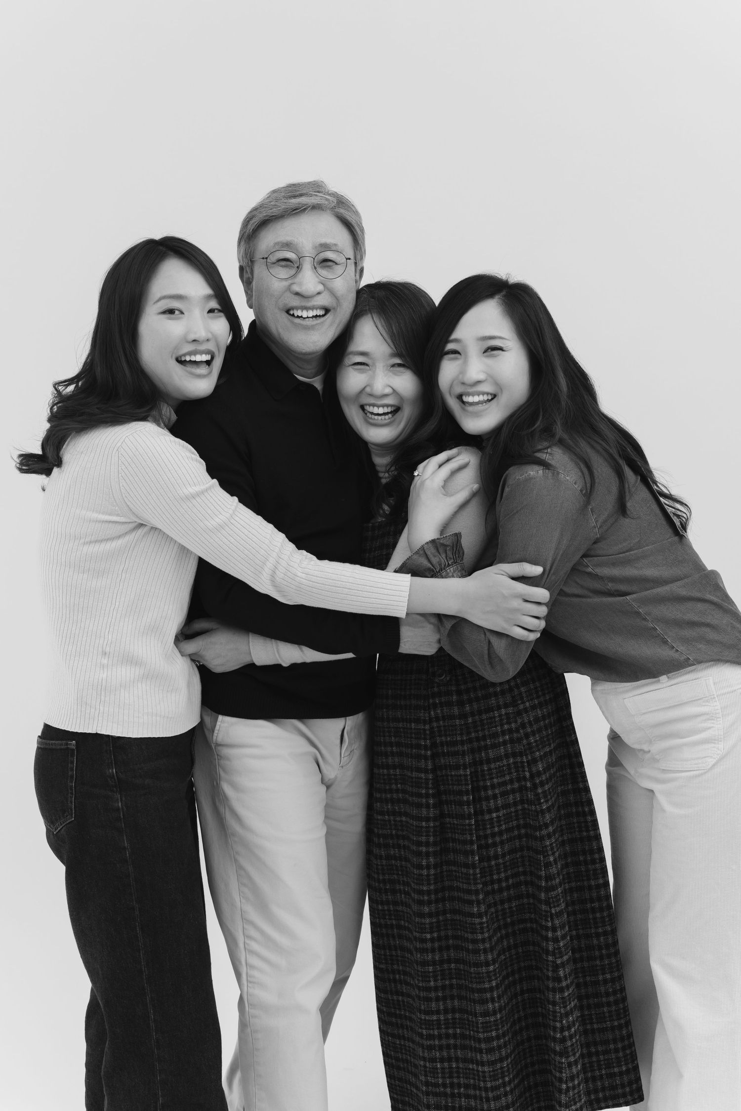A group of friends hugging and laughing together in a black and white photo series.
