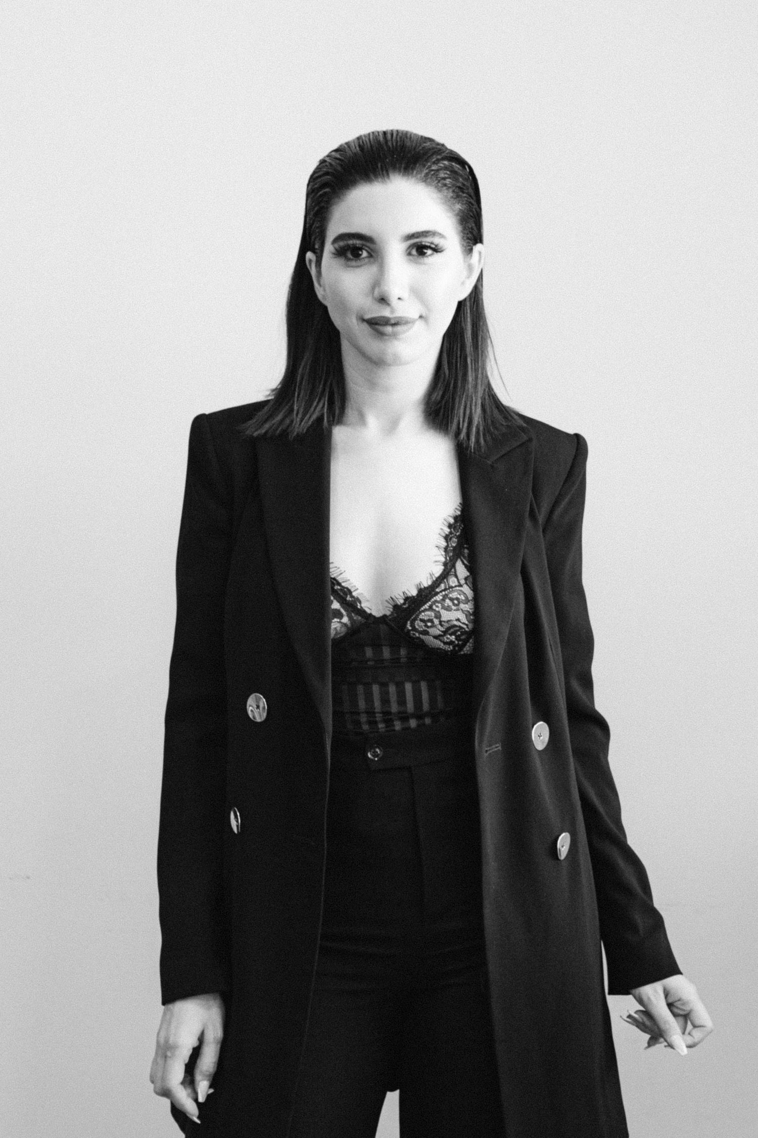 Black and white fashion portraits showing a person in a black blazer and lace top against a light background.