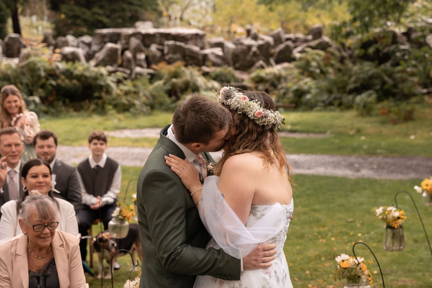 A wedding ceremony takes place in the courtyard of a historic stone church with guests gathered around.
