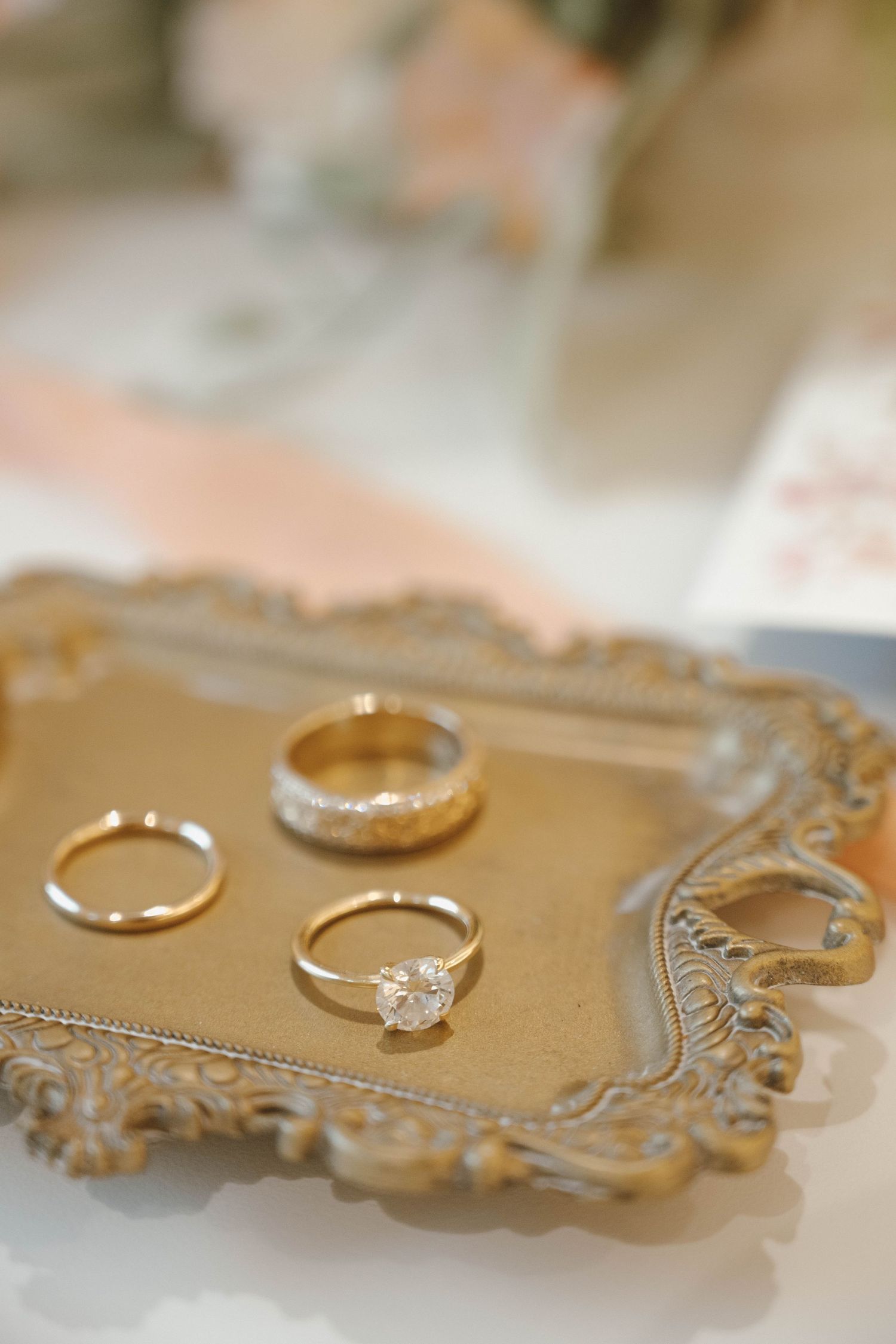 Wedding rings and jewelry displayed on an ornate gold-toned decorative tray in detail shots.
