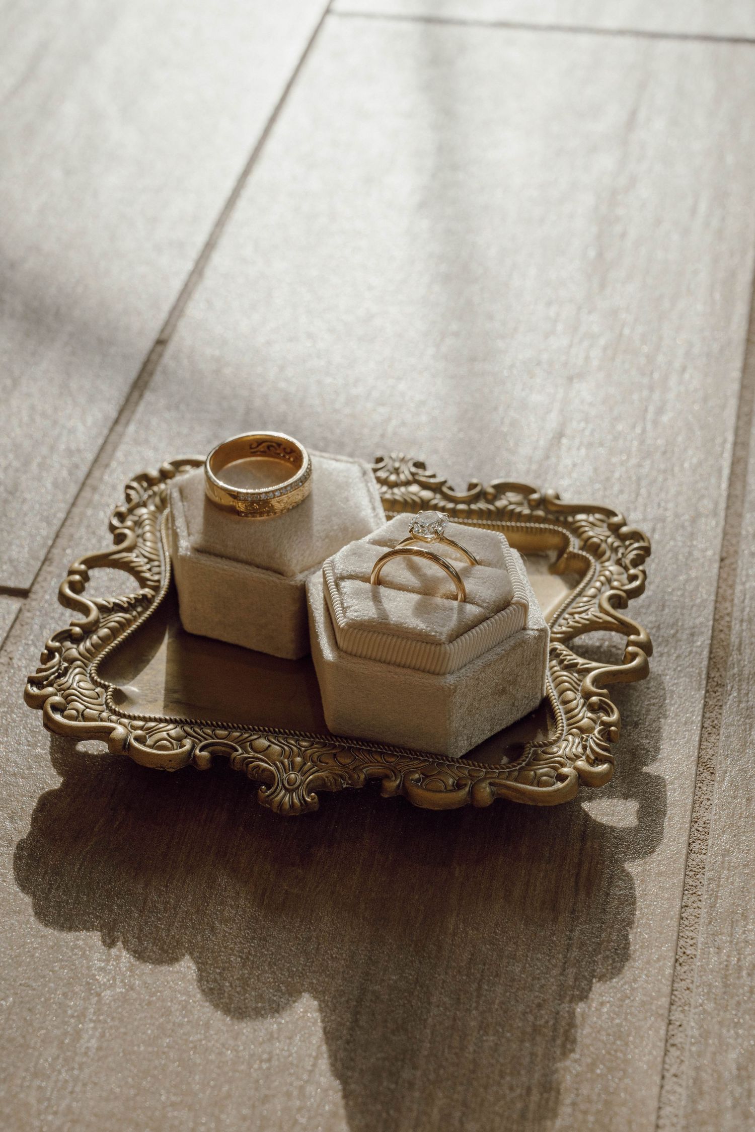 Wedding rings and jewelry boxes arranged on an ornate vintage silver tray with delicate patterns.
