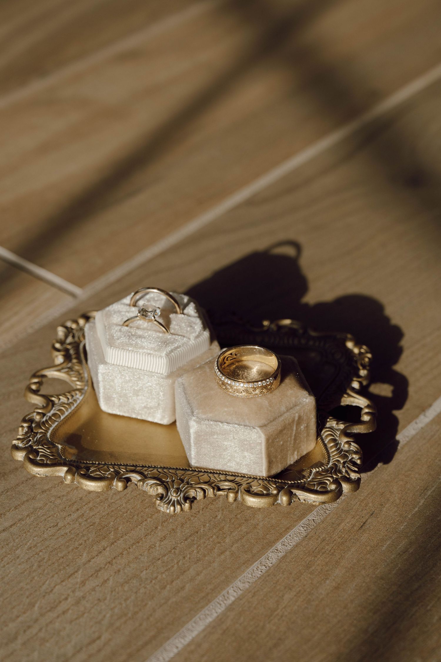 Wedding rings and decorative elements arranged on a wooden surface with dramatic shadows.