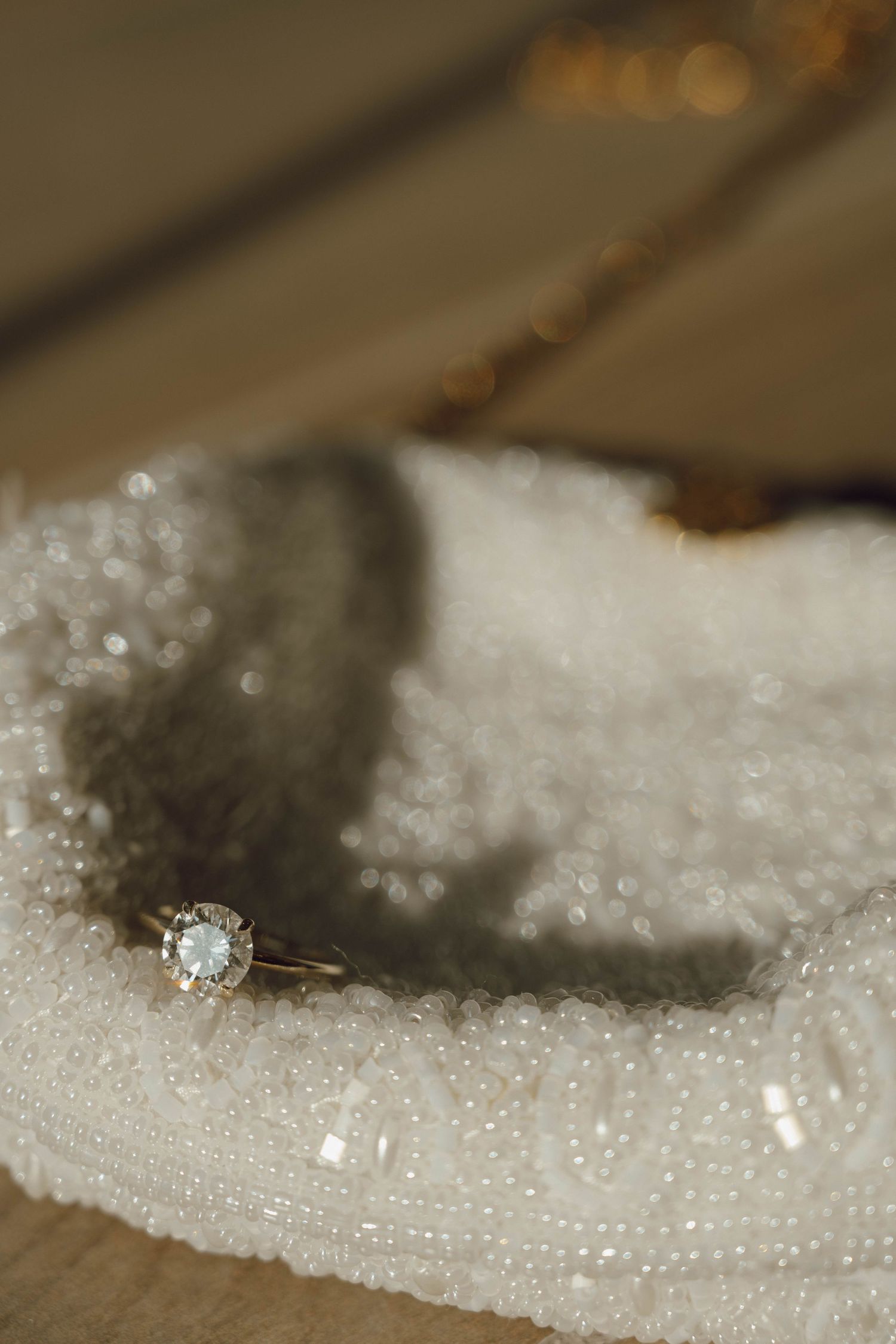Diamond engagement ring nestled in sparkling white sugar crystals creating an ethereal macro photography scene.