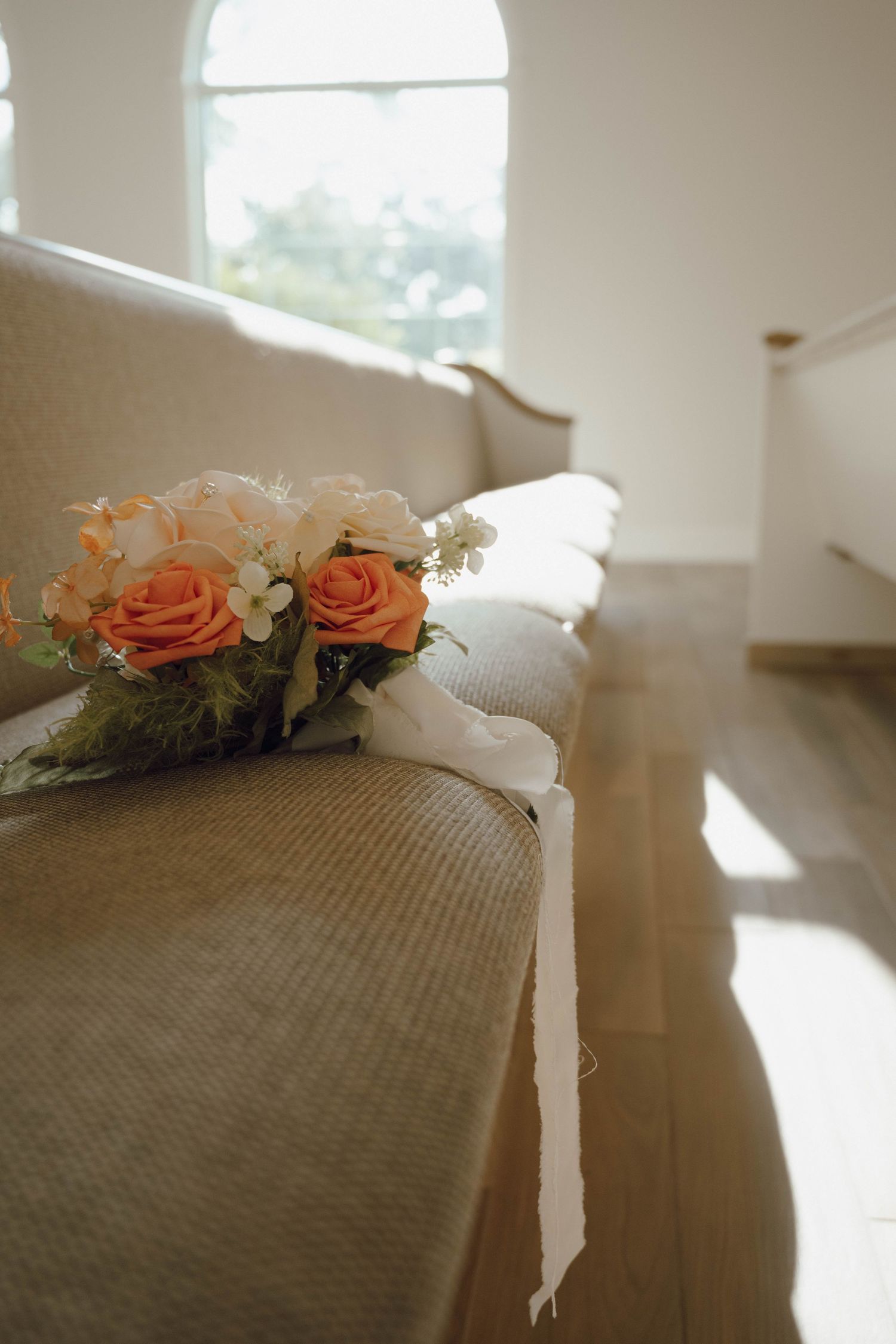 Peach and white roses with ribbon lay delicately on a textured gray surface in soft natural lighting.